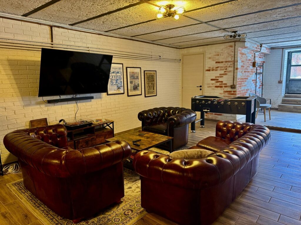Studio Bunker Roma: lounge con divani Chesterfield in pelle e mattoni a vista